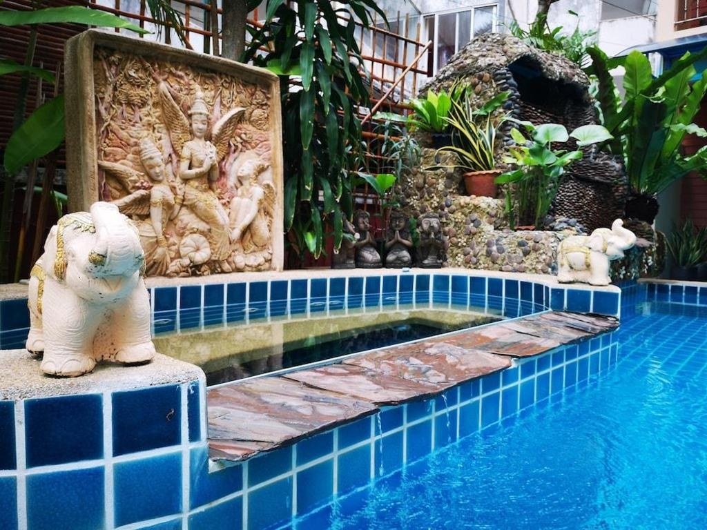 Piscine carrelée de bleu avec mur décoratif et plantes tropicales